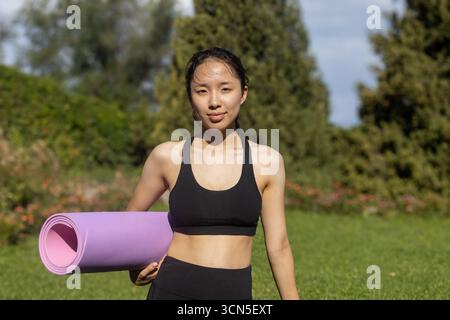 Frau in schwarzem BH, die eine Yoga-Matte hält Stockfoto