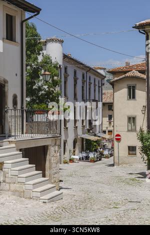 Blick auf verwitterte Steintreppen steigen zu einem Gebäude mit Blumenkästen, während sich enge Kopfsteinpflasterstraßen durch die Altstadt, Pescocostanzo, Abruzzen, Italien winden. Stockfoto
