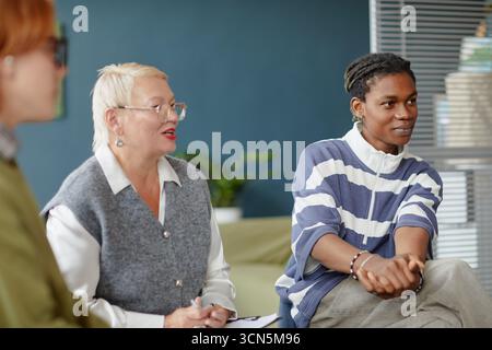 Verschiedene junge Erwachsene und Frauen mittleren Alters, die an Gruppendiskussionen teilnehmen Stockfoto