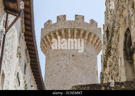 Der Blick auf einen alten Steinturm mit Zinnen reicht hoch unter dem hellen Himmel, umgeben von verwitterten Gebäuden, Santo Stefano di Sessanio, Abruzz Stockfoto