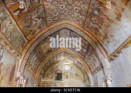 Blick auf lebendige Fresken an der gewölbten Decke einer mittelalterlichen Kirche, eine Symphonie der Farben und Geschichte, die Geschichten der Hingabe flüstert, Bominaco, Abruzzen, Italien. Stockfoto
