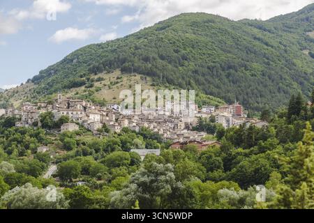 Blick auf die Altstadt eingebettet in ein Tal, umgeben von grünen Hügeln und üppigen Bäumen unter hellem Himmel, eine zeitlose Landschaft, Scanno, Abruzzen, Italien. Stockfoto