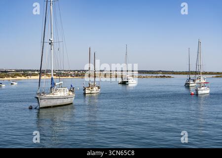 Segelboote vor Anker im Gilao River, vor dem Strand Praia da Ilha de Tavira, auf der Insel vor Tavira, Algarve, Portugal Stockfoto