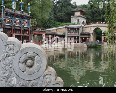 Ein ruhiger Blick auf ein traditionelles chinesisches Dorf entlang eines Sees, mit einer kunstvollen Steinbalustrade im Vordergrund, klassischer Architektur, einem steinbruchteil Stockfoto
