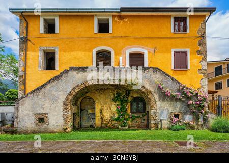 Casa colonica dipinta di ocra con facciata rustica, doppia scalinata in pietra, ingresso ad arco e graziose rose rampicanti. Posta Fibreno, Latium Stockfoto