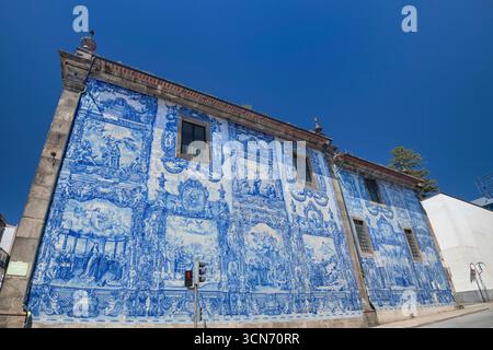Portugal, Porto, Seitenwand der Azulejo-verkleideten Capela das Almas oder Kapelle der Seelen aus dem 18. Jahrhundert, auch bekannt als Kapelle Santa Catarina mit 15.947 Azulejo-Fliesen, die von Eduardo leite entworfen wurden. Stockfoto
