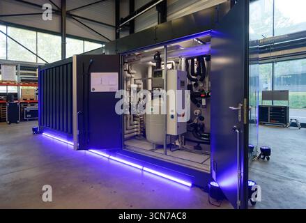 Aachen, Deutschland. September 2025. Eine große Wärmepumpe vom Typ EnerCube befindet sich in einer Halle der DFA-Demonstrationsfabrik Aachen auf dem Campus der RWTH Aachen. Die Container-großen Würfel enthalten eine große Wärmepumpe, die heißes Wasser und Wärme für Wohngebäude liefert. Die schalldichten Behälter sind auch in älteren bestehenden Gebäuden mit Heizkörpern zu verwenden. Die EnerCube Cubes sollen nun in Aachen in Serie produziert werden. Quelle: Henning Kaiser/dpa/Alamy Live News Stockfoto