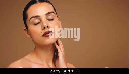 Hautpflege, Augen geschlossen und Frau im Studio, Schönheit und Dermatologie auf braunem Hintergrund. Glanz, Mockup Raum und Person mit Glühen, Wellness und Stockfoto