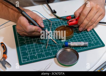 Nahaufnahme des Lötprozesses mit Eisen, Drähten und Werkzeugen Stockfoto