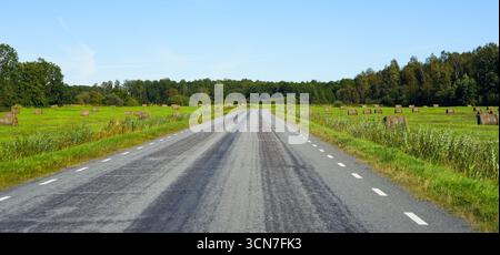 Landschaftlich reizvolle Landstraße mit Heuballen auf der Insel Saaremaa, Estland – Landschaft im Sommer im Baltikum Stockfoto
