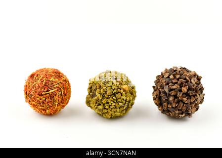 Drei verschiedenfarbige Kugeln, von denen eine braun ist. Die anderen beiden sind grün und orange. Die Bälle sitzen auf weißem Hintergrund Stockfoto