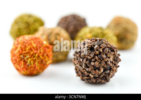 Eine Gruppe kleiner, runder, brauner und oranger Bonbons. Die Bonbons sind in einer Reihe angeordnet, wobei eine davon im Mittelpunkt steht. Die Süßigkeiten haben es Stockfoto