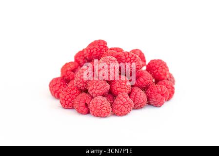 Ein Haufen roter Himbeeren auf weißem Hintergrund. Die Himbeeren sind klein und rot, und sie stapeln sich übereinander Stockfoto