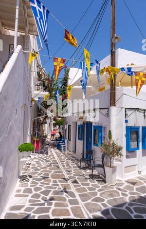 Parikia, Paros, GR - 22. August 2025: Eine Straße in der Altstadt von Parikia mit weißen Häusern und blau bemalten Details Stockfoto