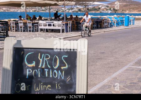 Parikia, Paros, GR - 22. August 2025: Restaurantschild mit Gyros mit Straßenszene in Parikia Stockfoto