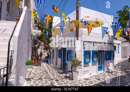Parikia, Paros, GR - 22. August 2025: Eine Straße in der Altstadt von Parikia mit weißen Häusern und blau bemalten Details Stockfoto