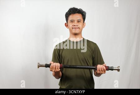 Asiatischer Mann mit grünem T-Shirt, der Krafttraining mit leichten Kurzhanteln macht Stockfoto