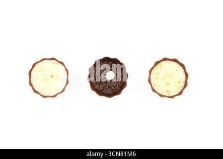 Drei Schokoladendesserts mit weißer Mitte. Die Nachspeisen sind in einer Reihe angeordnet, wobei der mittlere eine weiße Mitte hat Stockfoto