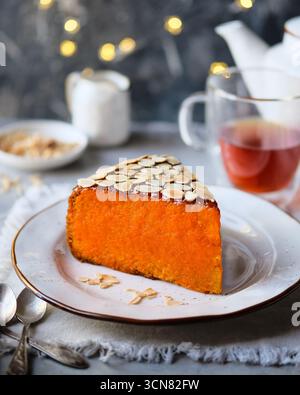 Genießen Sie einen bezaubernden Orangenkuchen mit knusprigen Mandeln und einer warmen Tasse Tee Stockfoto