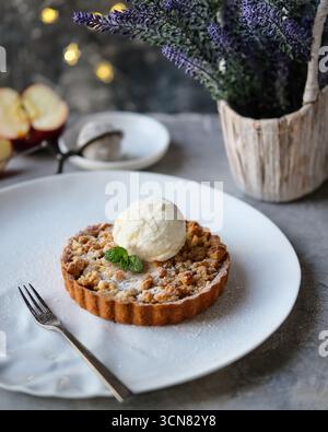 Genießen Sie eine köstliche Apfeltorte, begleitet von cremiger Eiscreme und frischen aromatischen Kräutern Stockfoto