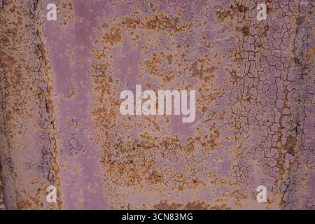 Nahaufnahme von rostiger, rissiger violetter Farbe auf alter Metalloberfläche. Konzept des Grunge-Hintergrunds, des veralteten Materials und der industriellen Textur. Stockfoto