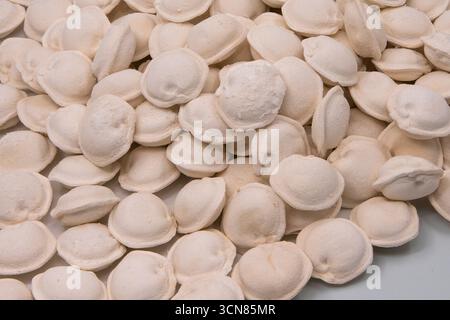 Stapel gefrorener Teigtaschen auf weißem Hintergrund. Rohe Pelmeni, zubereitet zum Kochen, repräsentiert traditionelle hausgemachte Speisen und praktische Kochen c Stockfoto
