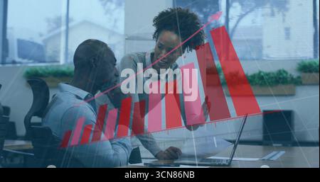 Zusammenarbeit am Schreibtisch, Analyse von Dokumenten auf einem Laptop durch zwei Experten, Überlagerung von Balkendiagrammen im Büro Stockfoto