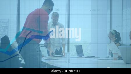 Mitarbeiter, die sich im Büro über einen Konferenztisch lehnen, mit Laptops und Dokumenten Stockfoto