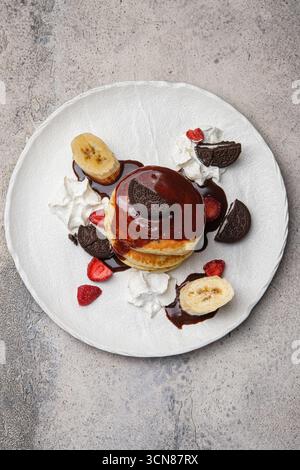 Genießen Sie einen Pfannkuchenstapel mit Schokoladensauce und frischem Obst zum Frühstück Stockfoto