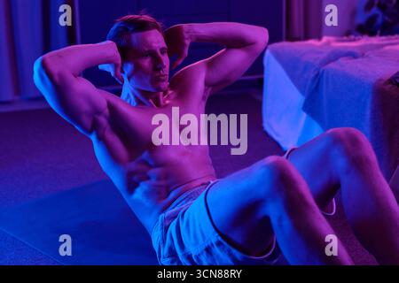 Mann, Der Die Rumpfmuskulatur Trainiert, Indem Er In Innenräumen Sit-Ups Durchführt Stockfoto