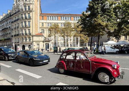 Paris, Frankreich. September 2025. Eine Straßenszene in Paris mit einem Vintage-roten Citroën 2CV und einem schwarzen Tesla-Elektrofahrzeug (EV), das am 6. September 2025 an einer Reihe eleganter Haussmann-Gebäude vorbeifährt. Fußgänger und andere Fahrzeuge teilen sich die breite Allee unter hellem, klarem Himmel. (Foto: Samuel Rigelhaupt/SIPA USA) Credit: SIPA USA/Alamy Live News Stockfoto