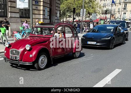 Paris, Frankreich. September 2025. Eine Straßenszene in Paris mit einem Vintage-roten Citroën 2CV und einem schwarzen Tesla-Elektrofahrzeug (EV), das am 6. September 2025 an einer Reihe eleganter Haussmann-Gebäude vorbeifährt. Fußgänger und andere Fahrzeuge teilen sich die breite Allee unter hellem, klarem Himmel. (Foto: Samuel Rigelhaupt/SIPA USA) Credit: SIPA USA/Alamy Live News Stockfoto