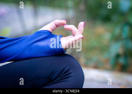 Junge asiatische Frau, die morgens im Park Yoga macht mit muslimischen Sportbekleidung. Gesunde Frau, die sich entspannt und Yoga im Stadtpark praktiziert. Stockfoto