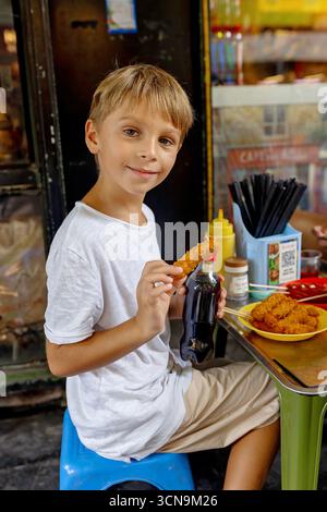 Kinder probieren Street Food in Hanoi, essen traditionelle vietnamesische Küche auf der Straße, kleine Tische und Stühle Stockfoto