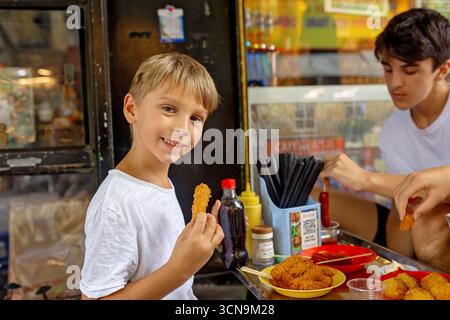 Kinder probieren Street Food in Hanoi, essen traditionelle vietnamesische Küche auf der Straße, kleine Tische und Stühle Stockfoto