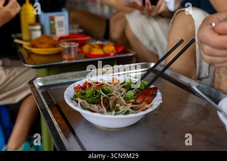 Kinder probieren Street Food in Hanoi, essen traditionelle vietnamesische Küche auf der Straße, kleine Tische und Stühle Stockfoto