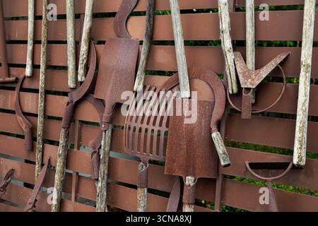 Alte rostige Gartenwerkzeuge auf einem Zaun Stockfoto
