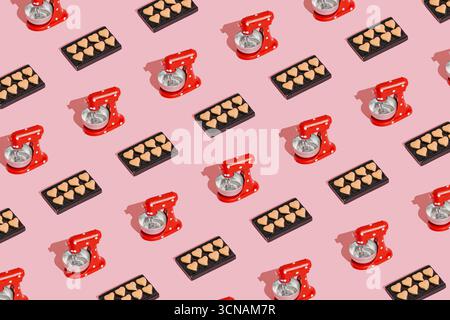 Stilvolles Kochmuster aus Mini-Standmixer-Modell mit herzförmigen Keksen auf pastellrosa Hintergrund. Stockfoto