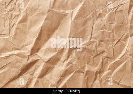 Braunes, zerknittertes Kraftpapier. Faltiger Oberflächenhintergrund für Konstruktion. Umweltfreundliches Verpackungsmaterial. Raues Papierblatt mit Falzen und Falten. Stockfoto