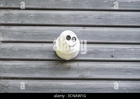 Sicherheitskamera an einer verwitterten Holzwand montiert, wahrscheinlich zur Überwachung und zum Schutz. Stockfoto