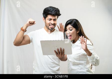 Ein aufgeregtes Paar, das zusammen feiert, während es sich ein Tablet ansieht. Stockfoto