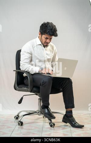 Ein junger Mann sitzt und benutzt einen Laptop. Stockfoto