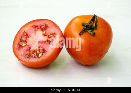 Frische, reife rote Tomaten ganz und halb isoliert auf hölzernem Hintergrund. Stockfoto