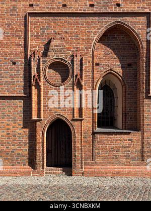 Blick auf die Vorderfassade der gotischen Backsteinkirche, die 1370 in Europa erbaut wurde, mit detaillierten bogenförmigen Eingängen und architektonischen Ornamenten. Historisch katholisch Stockfoto