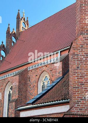 Detail der gotischen Backsteinkirche aus dem Jahr 1370 in Europa mit Dachlinie, Bogenfenstern und dekorativen Elementen. Beispiel eines mittelalterlichen katholischen Architekten Stockfoto