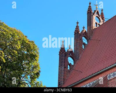 Nahaufnahme der gotischen Backsteinkirche aus dem Jahr 1370 in Europa mit Seitenwand, Dachlinie und dekorativen Türmen. Mittelalterliche katholische Architektur mit blauem SK Stockfoto
