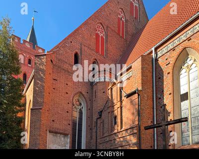 Weite Seitenansicht der gotischen katholischen Backsteinkirche, die 1370 in Europa erbaut wurde, mit hohen Bogenfenstern, Stützen und Dachlinie. Stockfoto