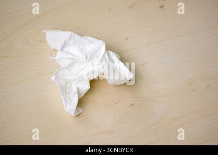 Ein gebrauchtes weißes Taschentuch auf hölzernem Hintergrund. Stockfoto