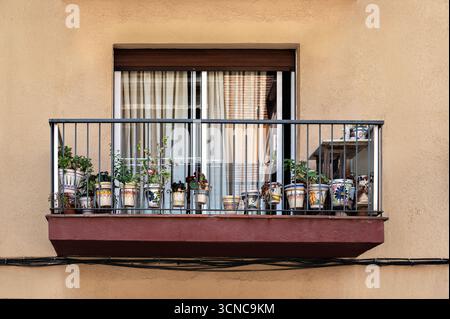 Balkon vor einer beigefarbenen Wand, dekoriert mit Blumen in Keramiktöpfen, in Arenys de Mar, Spanien. Aus der World Windows-Serie. Stockfoto
