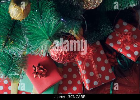 Ein Haufen festlicher Geschenke sitzt unter einem geschmückten Weihnachtsbaum Stockfoto
